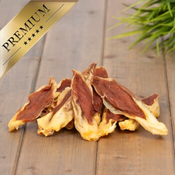 Ein Haufen hochwertiger Haustierleckerlis, bestehend aus zähen Streifen mit einer goldbraunen Außenseite und einem rötlich-braunen Zentrum, auf einer Holzoberfläche.