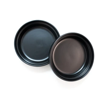 Zwei schwarze Haustierfutterschalen, die leicht schief auf einem weißen Hintergrund gestapelt sind, und ihre glatte, glänzende Oberfläche zeigen.