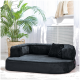 Schwarzes Haustiersofa mit einer plüschigen Oberfläche und einem kleinen Kissen, platziert in einem hellen Raum mit einer Topfpflanze im Hintergrund.