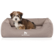 Flauschiger braun-weißer Welpe in einem taupefarbenen rechteckigen Hundebett mit weißem 'KNUFFELWUFF'-Logo.