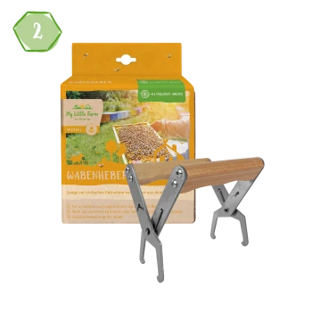 Ein Wabenheber-Werkzeug aus Metall und Holz wird mit seiner grünen und orangefarbenen Verpackung gezeigt, die mit "Wabenheber" und "My Little Farm" beschriftet ist.