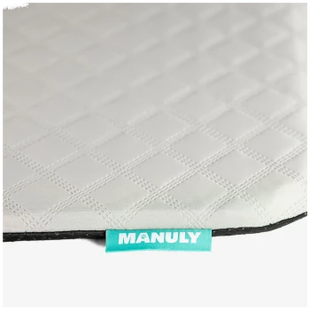 Hellgraue, im Rautenmuster gesteppte Haustiermatte mit schwarzer Einfassung und türkisfarbenem Etikett mit der Aufschrift 'MANULY'.