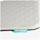 Hellgraue, im Rautenmuster gesteppte Haustiermatte mit schwarzer Einfassung und türkisfarbenem Etikett mit der Aufschrift 'MANULY'.