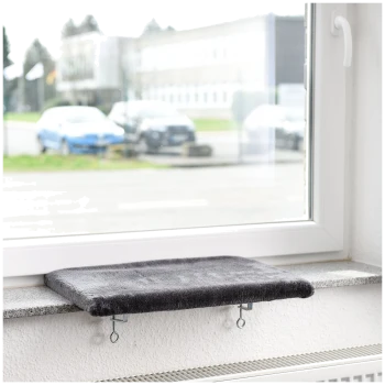 Eine graue Fensterbank für Haustiere, die an einer weißen Wand befestigt ist und auf eine Straße mit geparkten Autos draußen blickt.