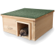 Ein Holzhaus für Igel mit einem grünen strukturierten Dach, mit einem Igel, der aus dem Eingang schaut.