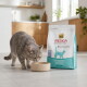 Chat gris buvant dans un bol beige à côté d'un sac de nourriture pour chats Select Gold Medica Veterinary Diet Hypoallergen