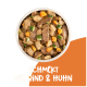 Oranger Hintergrund mit weißem Text: "Schmeckt wie Rind & Huhn," listet Vorteile wie glutenfrei, hoher Proteingehalt und gesunde Haut auf.