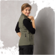 Eine Frau in einer grünen Weste und einem schwarzen Langarmshirt posiert mit dem Rücken zur Kamera und zeigt die Reißverschlüsse und Taschen der Weste.
