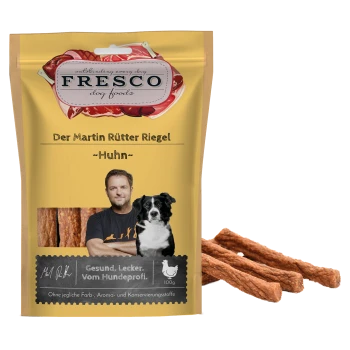 Gelbe Fresco-Tüte mit der Aufschrift "Der Martin Rütter Riegel - Huhn", zeigt ein verschwommenes Männerfoto neben einem Hund, Hähnchen-Leckerlis, 100 g.
