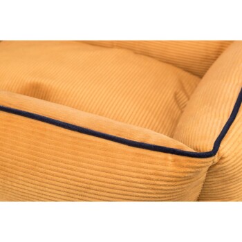 Nahaufnahme eines plüschigen, senfgelben Haustierbettes mit einer gerippten Textur und einem dunkelblauen Rand entlang der Kanten.