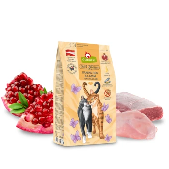 GranataPet DeliCATessen Katzenfutterbeutel, "Kaninchen & Lamm," mit einer schwarz-orangefarbenen Katze, Granatapfelkernen und rohen Fleischstücken.