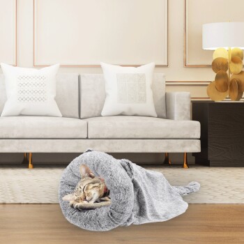 Eine gemütliche graue Katzendecke mit einer schlafenden getigerten Katze, die darin eingerollt ist, in einem stilvollen Wohnzimmer mit einem hellen Sofa und dekorativen Kissen.