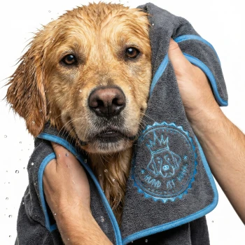Ein gerolltes, dunkelgraues Haustierhandtuch mit blauen Akzenten, mit einem gestickten Design eines Hundegesichts und dem Text 'Hund ist König.'