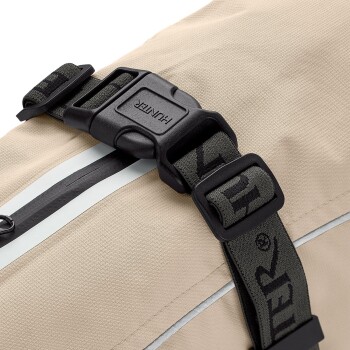 Nahaufnahme eines beigen Haustier-Rucksacks mit einer schwarzen Kunststoffschnalle mit "HUNTER"-Markierung und einem Reißverschlussdetail.