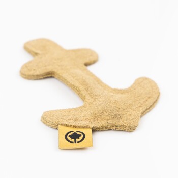 Ein beigefarbenes, plüschiges Hundespielzeug in Form eines Knochens, mit einem kleinen gelben Etikett mit einem schwarzen Logo.