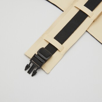 Nahaufnahme eines beigen Haustiergeschirrriemens mit einer schwarzen verstellbaren Schnalle und einem elastischen Band, vor einem weißen Hintergrund.