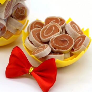 Gelbe Schüssel gefüllt mit spiralförmigen Haustiersnacks und einer roten Fliege auf weißem Hintergrund.