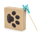 Ein Karton in Form eines Pfotenabdrucks mit schwarzen runden Ausschnitten, begleitet von einem blauen, flauschigen Spielzeug an einem Stock, das einem kleinen Tier ähnelt.