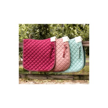 Drei gesteppten Satteldecken in Burgunderrot, Blush-Pink und Mintgrün, die an einem Holzzaun hängen, umgeben von Grün.