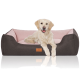 Ein Golden Retriever Welpe ruht sich bequem auf einem stilvollen Hundebett mit dunklem grauen Äußeren und weichem rosa Innenraum aus.