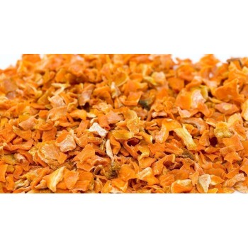 Getrocknete orange Karottenflocken, die auf einer weißen Oberfläche verstreut sind und ihre lebendige Farbe und Textur zeigen.