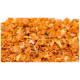 Getrocknete orange Karottenflocken, die auf einer weißen Oberfläche verstreut sind und ihre lebendige Farbe und Textur zeigen.