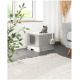 Eine graue Katze sitzt in einer stilvollen, modernen Katzentoilette mit einem gesteppten Design, die in einem hellen Raum mit einem Teppich und einem Sofa platziert ist.