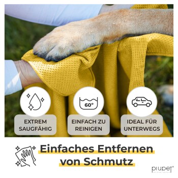 Eine Person hält ein gelbes Reinigungstuch mit einem Hundepfotenabdruck darauf, mit Text über Saugfähigkeit, einfache Reinigung, Tragbarkeit und Schmutzentfernung.