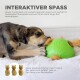 Ein verspielter Hund interagiert mit einem grünen Puzzleballspielzeug, aus dem Leckereien herausgezogen werden, mit Text, der seine interaktiven Funktionen und Nachfülloptionen hervorhebt.