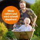 Eine Person in einem karierten Hemd schiebt eine Schubkarre mit einem Kind, umgeben von Grün. Ein orangefarbener Kreis sagt: 'Wirkt sofort und wird schnell abgebaut.'