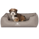 Ein kleiner, flauschiger Hund sitzt bequem in einem grauen Hundebett mit erhöhter Rückenlehne, das das Logo "KNUFFELWUFF" deutlich zeigt.