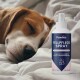 Ein schlafender Beagle liegt auf einer weichen Oberfläche neben einer Flasche Pawlie's Fellpflege Spray, beschriftet mit "100% natürliche Inhaltsstoffe" und "0% Alkohol."