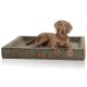 Ein brauner Hund, der auf einem plüschigen, olivgrünen Haustierbett mit gerippter Textur und einem kleinen Logo-Tag an der Seite entspannt.