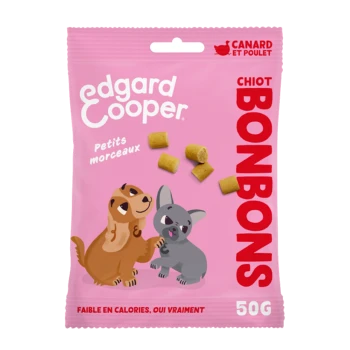Un sac rose de friandises pour chiens Edgard Cooper avec un chien et un chiot en dessin animé, avec le texte "Petits morceaux" et "BONBONS" affiché en évidence.
