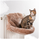 Ein gemütliches, plüschiges Katzenbett, das an einem Heizkörper befestigt ist, mit einer getigerten Katze, die bequem darauf sitzt.