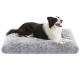 Schwarz-weißer Border Collie liegt auf einem großen, flauschigen grauen Haustierbett vor weißem Hintergrund.