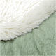 Een close-up van een zacht huisdierbed met een pluizige witte bovenlaag en een gestructureerde lichtgroene onderlaag.