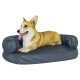 Ein glücklicher Corgi, der auf einem dunkelblauen Haustierbett mit erhöhten Seiten liegt, und seine verspielte Miene und entspannte Haltung zeigt.