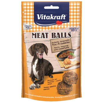Meat Balls 7x87g Ein Hund mit einem glücklichen Ausdruck sitzt neben einem Paket von Vitakraft Fleischbällchen, mit Bildern von Fleischbällchen und Zutaten.