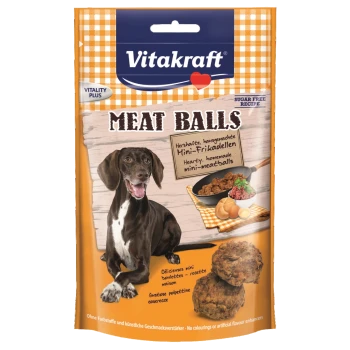 Ein Hund mit einem glücklichen Ausdruck sitzt neben einem Paket von Vitakraft Fleischbällchen, mit Bildern von Fleischbällchen und Zutaten.
