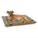 Ein entspannter brauner Hund liegt auf einem plüschigen, olivgrünen Hundebett mit gestepptem Design und einem kleinen Logo-Tag.