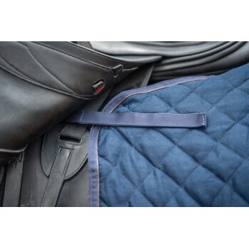 Nahaufnahme eines schwarzen Ledersattels und eines blauen gesteppten Sattelpolsters, mit einem Riemen zur Befestigung.