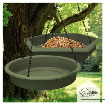 Hängendes Vogelfutterset mit einem sechseckigen Tablett, das mit Vogelfutter gefüllt ist, und einem runden Tablett darunter, vor einem üppig grünen Hintergrund.