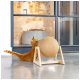 Un chat tigré orange s'étire joyeusement et gratte un poteau à gratter en sisal rond sur un support en bois dans un espace intérieur moderne.