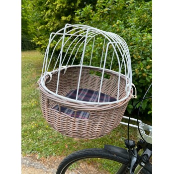 Ein Korb für Haustiere mit einem weißen Metallkäfig oben, der an einem Fahrrad befestigt ist, mit einem karierten Kissen innen, vor einem grünen Hintergrund.