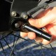 Eine Nahaufnahme einer Hand, die ein schwarzes Fahrradteil greift und eine Schraube in der Nähe der Radnabe anpasst, mit sichtbaren Metallteilen und Werkzeugen.