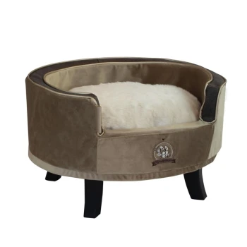 Sessel Cute Pets taupe Ein plüschiges, rundes Haustierbett in Beige mit einem weichen weißen Kissen innen, mit schwarzen Holzbeinen und einem gestickten Logo an der Seite.