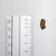 Kleines braunes, gebogenes Leckerli-Pellet (ca. 1 cm lang) neben einem metrischen Lineal, das die 0-cm-Markierung auf weißem Hintergrund zeigt.