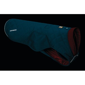Eine blaue, gesteppten Hundejacke von Ruffwear, mit maroonem Innenfutter und reflektierendem Rand, vor einem schwarzen Hintergrund präsentiert.