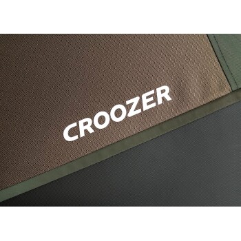 Nahaufnahme einer Stoffoberfläche mit dem Markennamen "CROOZER" in fetten weißen Buchstaben, mit einem strukturierten braunen und grünen Hintergrund.